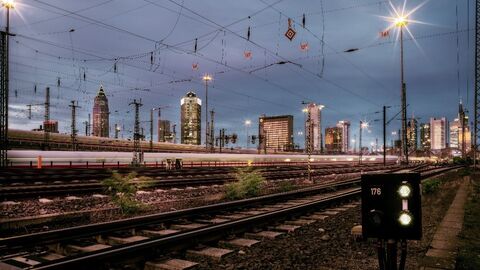 Bahngleise vor einem Nachthimmel und der beleuchteten Skyline von Frankfurt am Main
