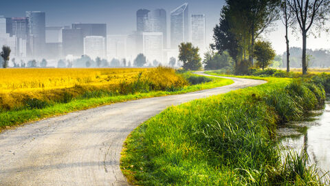 Feld und Feldweg mit skizzierter Stadt im Hintergrund